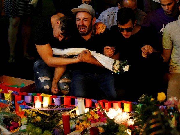 Homens se abraçam e dão as mãos emocionados durante vigília à luz de velas em memória às vítimas do atirador na boate gay Pulse, em Orlando, na Flórida (EUA) (Foto: Carlo Allegri/Reuters)