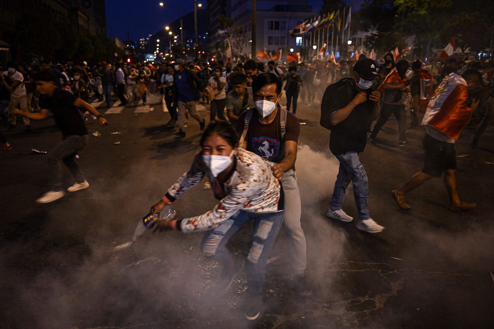Apoiadores do ex-presidente Pedro Castillo se escondem do gás lacrimogêneo lançado pela polícia durante uma manifestação exigindo sua libertação e o fechamento do Congresso peruano, em Lima — Foto: ERNESTO BENAVIDES / AFP