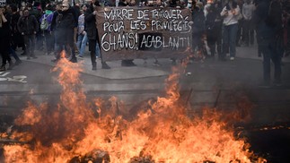 Manifestantes seguram um cartaz onde se lê "Estamos cansados de pagar por pessoas privilegiadas" — Foto: LOIC VENANCE / AFP