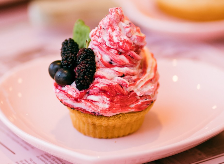 O buttercream do cupcake é tingido com amoras maceradas e finalizado com frutas frescas e hortelã