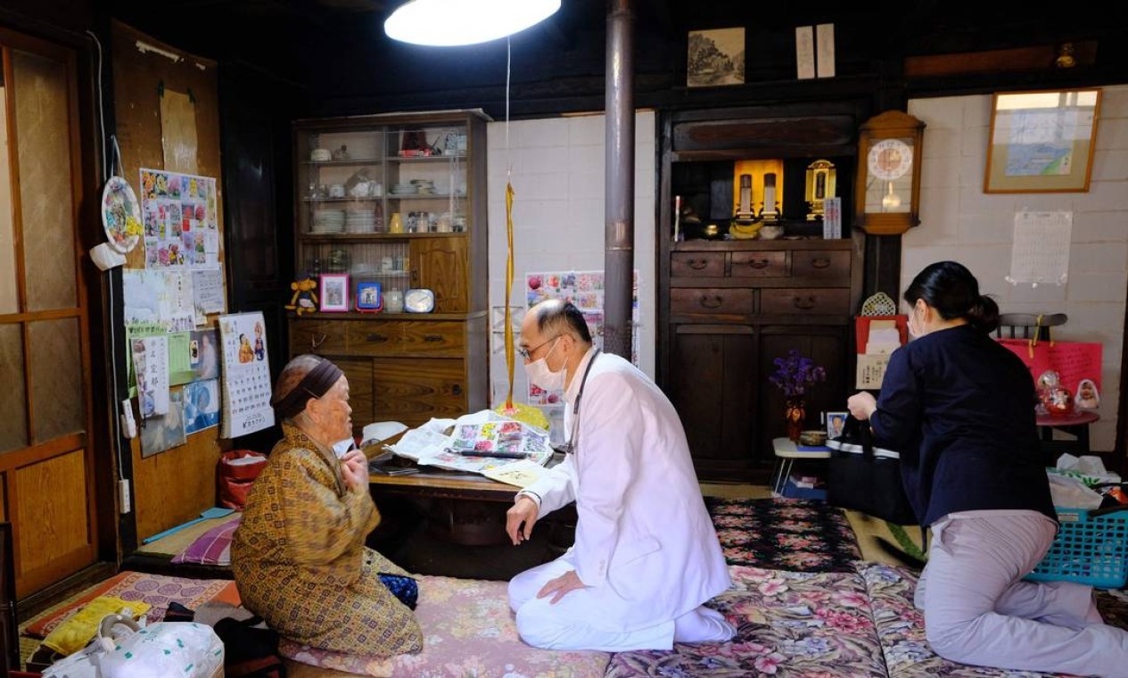 Profissionais de saúde conversam com Kakino Yamaguchi, depois de chegar a sua casa para inoculá-la com a vacina de coronavírus Pfizer-BioNTech Covid-19, na vila de Kitaaiki, onde vivem cerca de 350 famílias, na província de Nagano, no Japão — Foto: KAZUHIRO NOGI / AFP