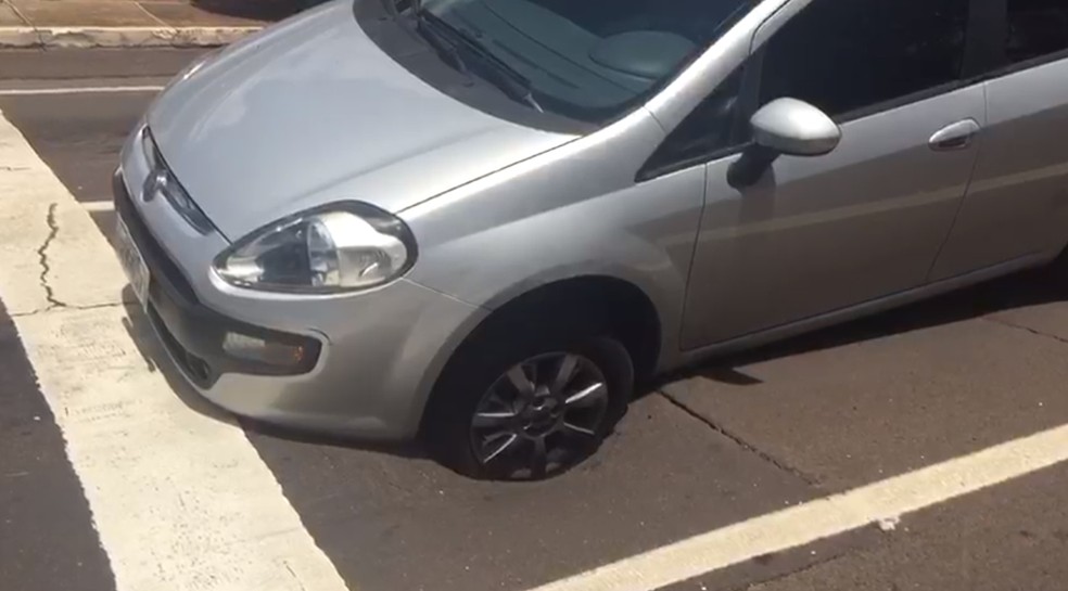 O motorista disse que estava parado no semÃ¡foro quando o asfalto cedeu e a roda do veÃ­culo ficou presa. â Foto: FlÃ¡vio Dias