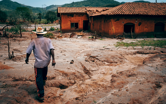 Um agricultor caminha por Paracatu de Baixo,uma das comunidades destruidas pela lama (Foto: YASUYOSHI CHIBA/AFP)