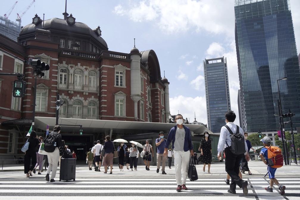 Pessoas caminham por cruzamento perto de estação em Tóquio, em 29 de julho de 2021. Sede das Olimpíadas, a capital japonesa registrou o 3º dia seguido de recorde de casos de Covid-19. — Foto: Kantaro Komiya/AP