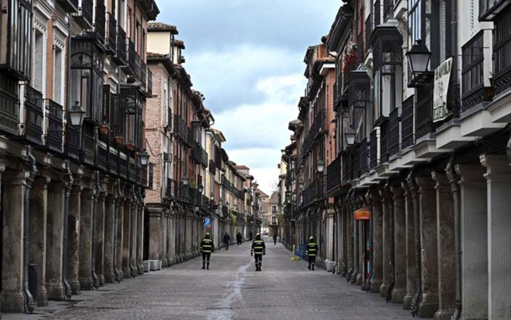 Na cidade de Alcala de Henares, perto de Madri, policiais fazem a ronda em uma rua vazia. Na Espanha, pessoas estão proibidas de sair de casa, exceto para comprar suprimentos essenciais e medicamentos, ou ir ao trabalho  — Foto: Fernando Villar/EPA/BBC