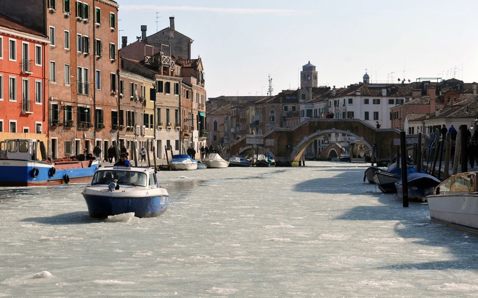 Barco passa em meio ao gelo acumulado nas águas dos canais de Veneza, na Itália. O frio intenso transformou a paisagem da cidade, famosa por suas vias aquáticas. — Foto: Marco Sabadin/AFP