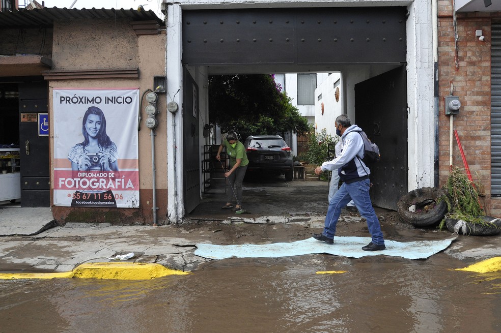Chuva atingiu diversos estados do México na noite desta segunda (6); Em Ecatepec, mulher tenta tirar lama de estabelecimento comercial — Foto: Claudio Cruz/AFP
