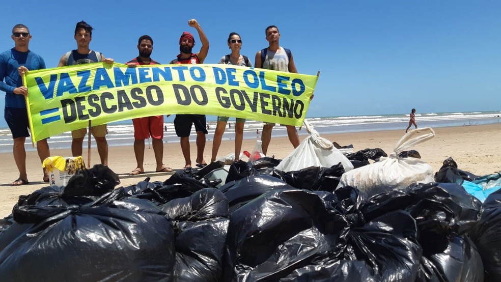 O voluntário Flávio Marcel, com o braço erguido, é um dos que ajudam a limpar a praia Cinelândia, em Aracaju — Foto: Arquivo Pessoal