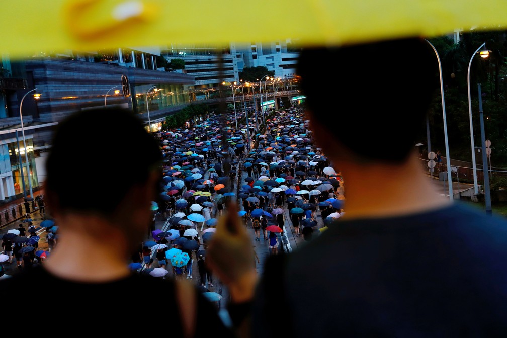 Espectadores observam manifestantes em Hong Kong, neste domingo (18)  — Foto: Tyrone Siu/ Reuters