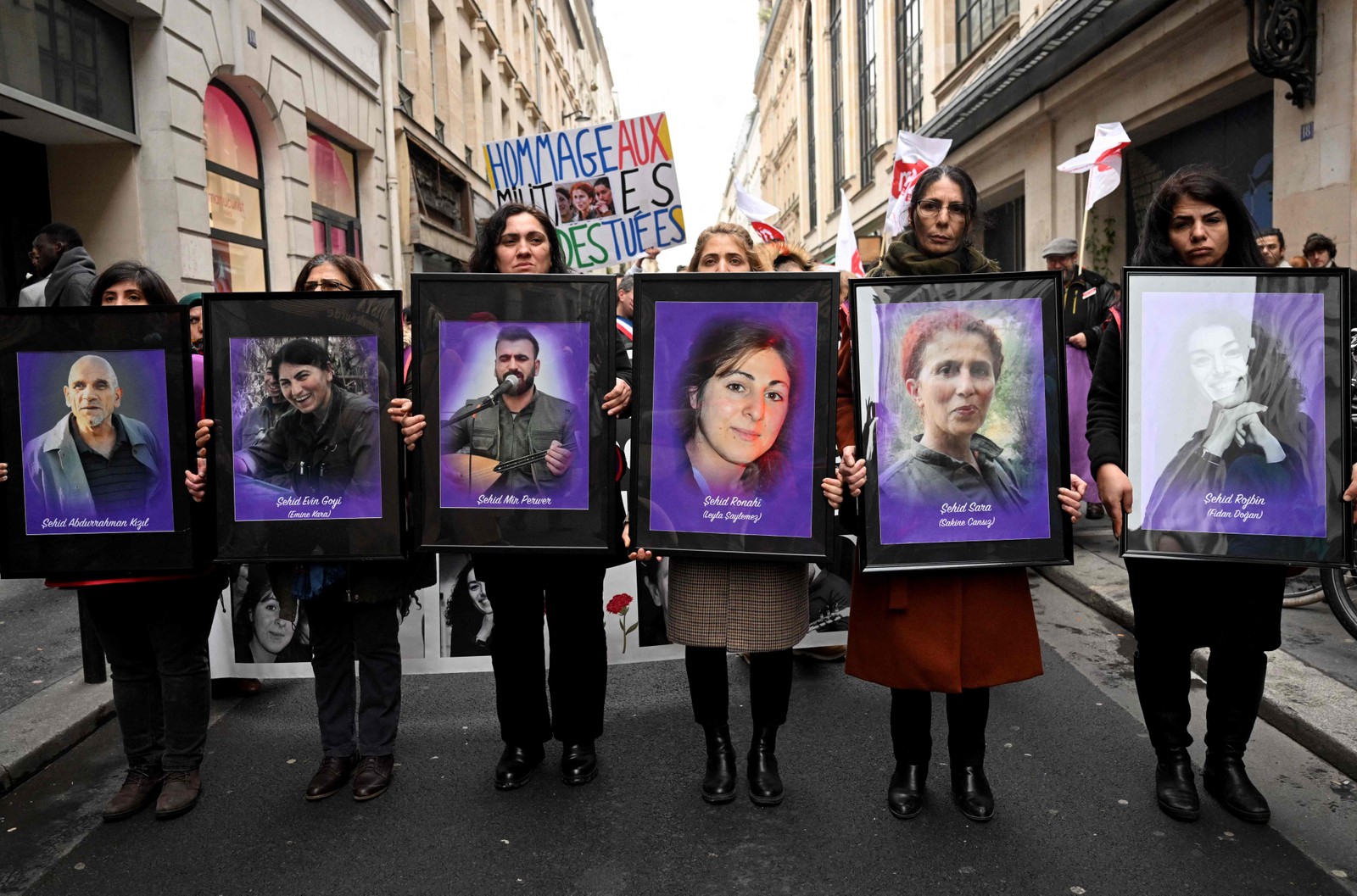 Manifestantes seguram retratos de ativistas curdos assassinados, durante uma marcha de tributo em Paris — Foto: Emmanuel Dunand/AFP