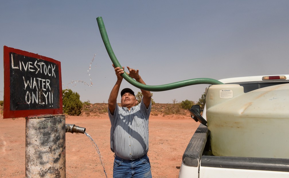 Eugene Boonie, de 55 anos, enche seu tanque de água em uma torneira de água para gado no Bodaway Chapter, na reserva Navajo. 'Temos que vir aqui para buscar água dia sim, dia não', disse ele. 'Costumávamos conseguir água da chuva, mas não tem chovido neste verão ou mesmo nos últimos anos.' — Foto: Stephanie Keith/Reuters