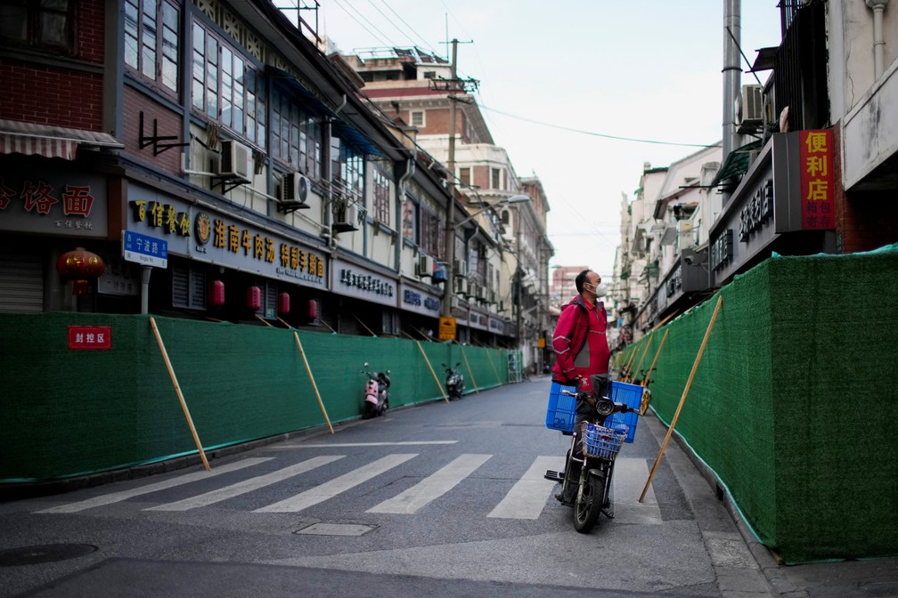 Entregador olha por cima de cerca montada para isolar área residencial em Xangai para controle de Covid, em maio deste ano — Foto: Aly Song/Reuters