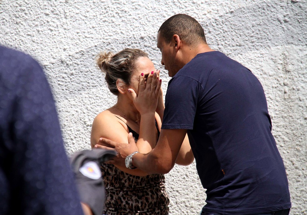 Um homem tenta acalmar uma mulher na entrada da Escola Estadual Raul Brasil em Suzano, na Grande São Paulo. Dois criminosos encapuzados mataram oito pessoas no local e cometeram suicídio em seguida — Foto: Maurício Sumiya/Futura Press via AP