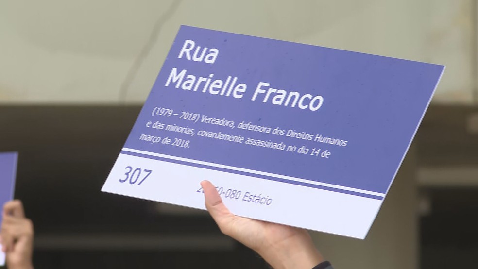 Participantes do ato seguram placas idênticas à que foi instalada em frente à Câmara dos Vereadores do Rio de Janeiro, com o nome Marielle Franco — Foto: TV Globo/Reprodução