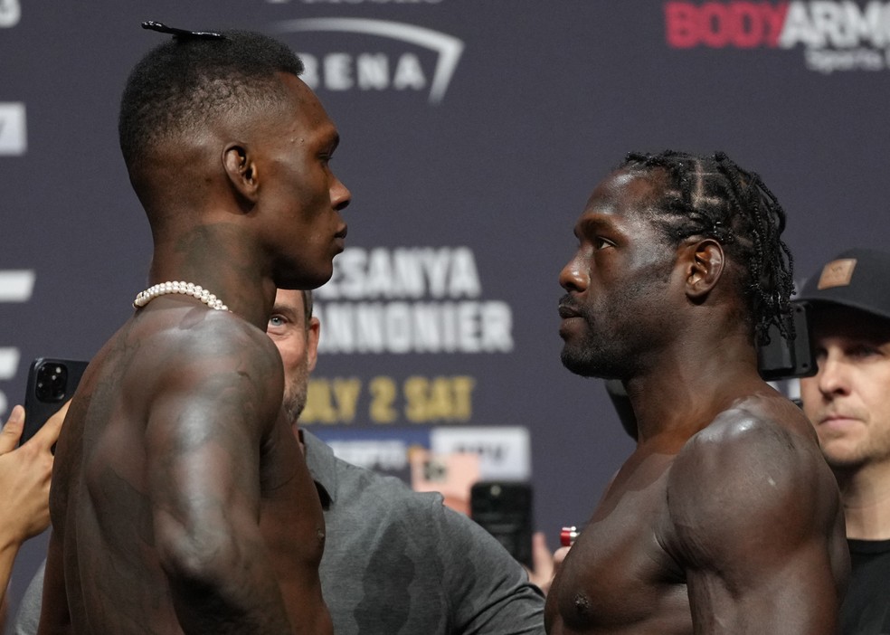 Israel Adesanya (esq.) e Jared Cannonier (dir.) fizeram longo olho no olho na pesagem do UFC 276 — Foto: Jeff Bottari/Zuffa LLC