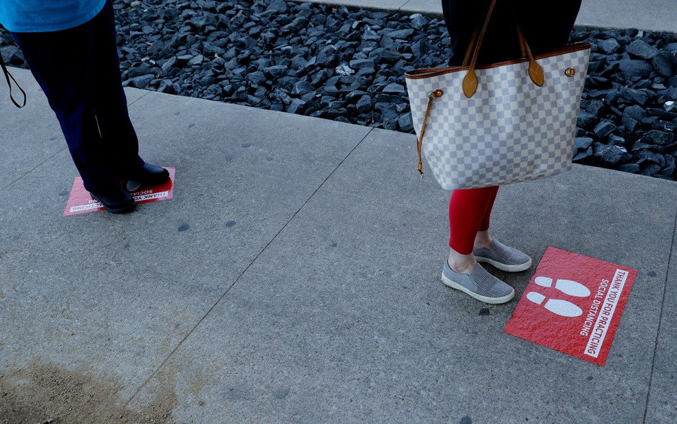 25 de março - Sinais que auxiliam no distanciamento social são usados ​​por compradores que esperam na fila de um supermercado em Austin, Texas, nos EUA. Os moradores da cidade estão sob ordens de ficarem em casa para ajudar a combater a propagação do novo coronavírus — Foto:  Eric Gay/AP