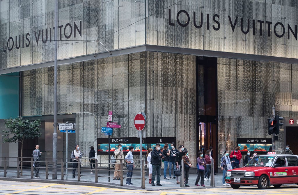 Pedestres de máscaras em frente a loja da Louis Vuitton em Hong Kong (Foto: Getty)