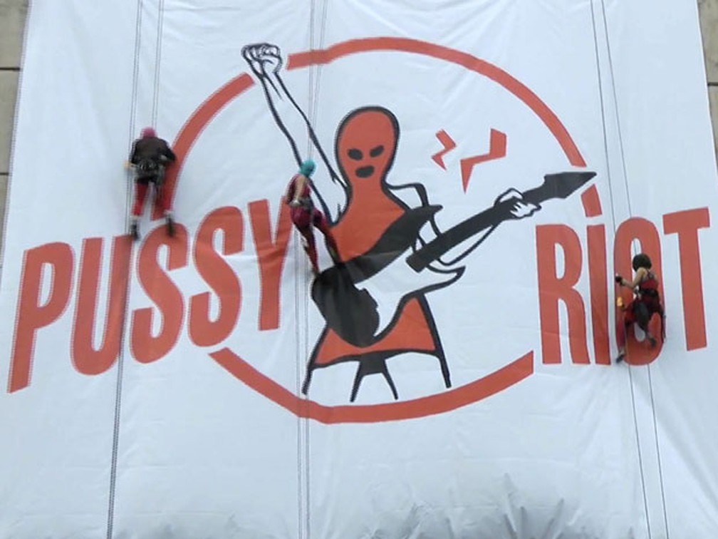 Cena do novo clipe do grupo Pussy Riot mostra cartaz gigante da banda sendo colocado em prÃ©dio abandonado (Foto: AP/APTN)