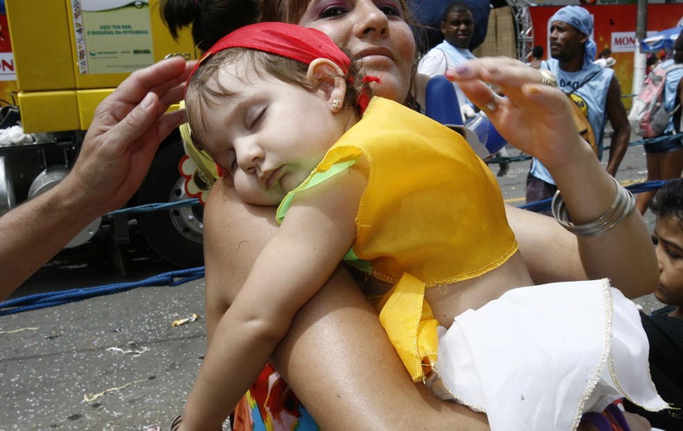 Criança fantasiada dorme no colo da mãe no carnaval em Salvador (Foto: Arestides Baptista / Agência A Tarde / Agência Estado)