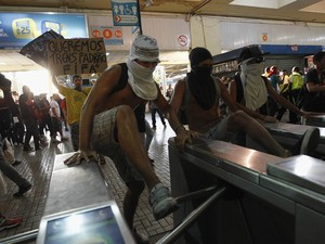 Manifestantes mascarados usam os pés para forçar e quebrar catracas da estação de metrô durante protesto no Rio (Foto: André Mourão/Agência O Dia/Estadão Conteúdo)