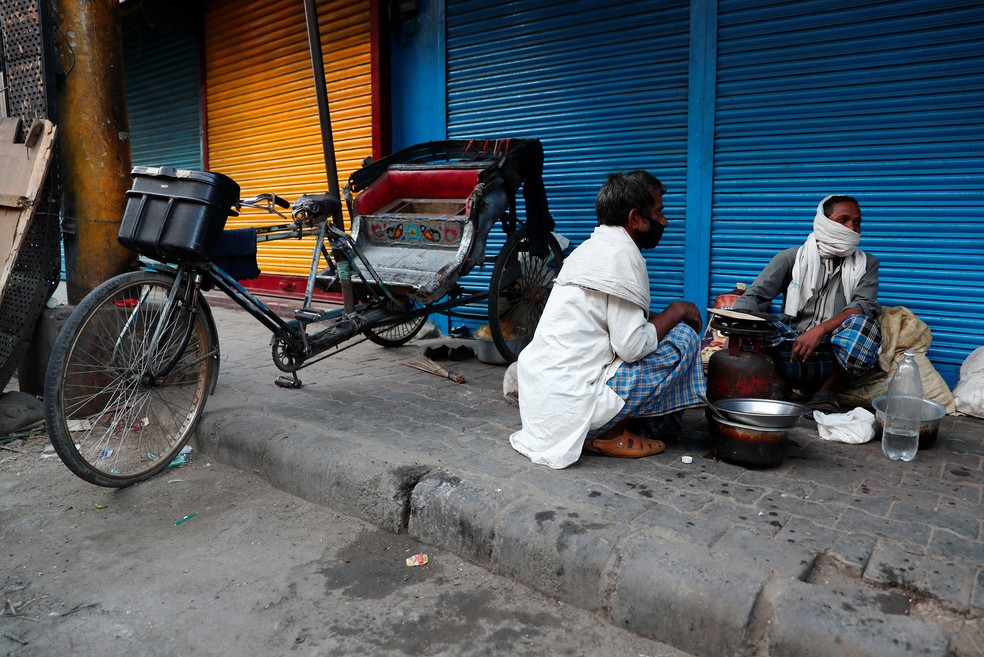 Trabalhadores migrantes cozinham em calçada de Nova Délhi, na Índia, nesta sexta-feira (3)  — Foto: Adnan Abidi/ Reuters