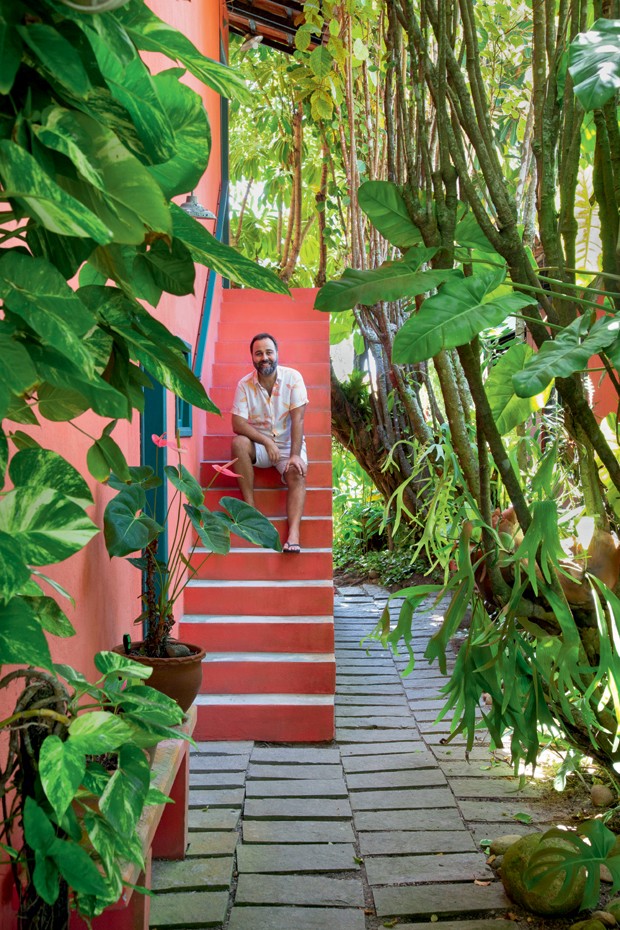O arquiteto Francisco Palmeiro sentado na escada .À frente, antúrios e filodendros (Foto: Juliano Colodeti / MCA Estúdio / Divulgação)