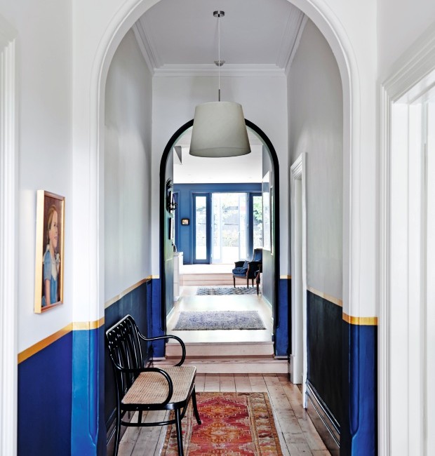 Corredor. O azul se estendeu para a passagem que liga os fundos da casa aos quartos. A parede foi pintada até a metade. Acima há uma faixa dourada, em sintonia perfeita com a cor da moldura do quadro (Foto: Lisa Cohen / Living Inside)
