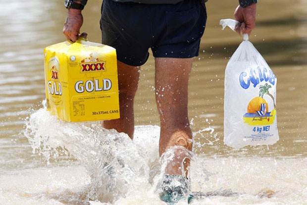 Em janeiro de 2011, um homem foi visto andando em uma rua alagada em  Rockhampton, Queensland, na Austrália, enquanto carregava uma caixa de cerveja e gelo (Foto: Reuters)