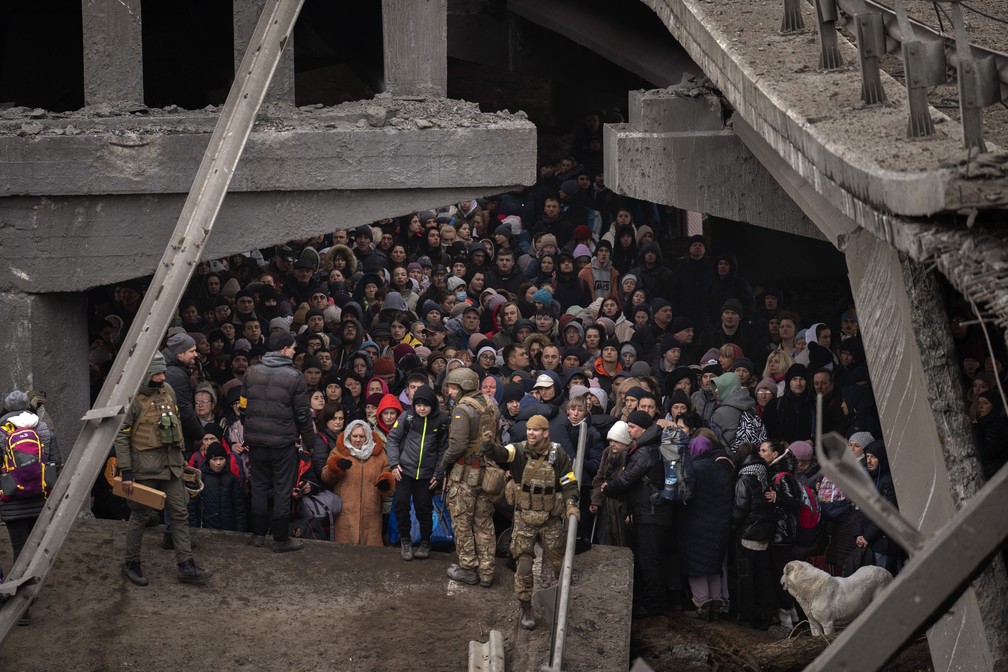Ucranianos se aglomeram sob uma ponte destruída enquanto tentam fugir atravessando o rio Irpin nos arredores de Kiev, Ucrânia, sábado, 5 de março de 2022. — Foto: AP Photo/Emilio Morenatti