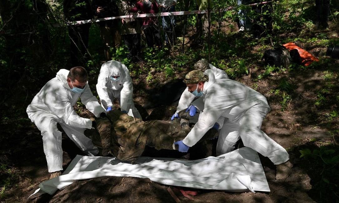 Especialistas forenses exumam o corpo de um soldado russo na vila de Zavalivka, a oeste de Kiev  — Foto: SERGEI SUPINSKY / AFP