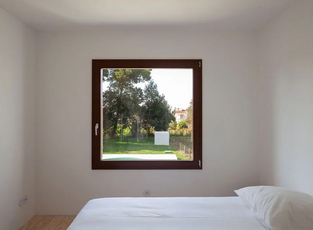 Mais simples impossível: o quarto conta com cama de casal e é iluminado pela janela quadrada na lateral (Foto: José Campos/ Designboom/ Reprodução)