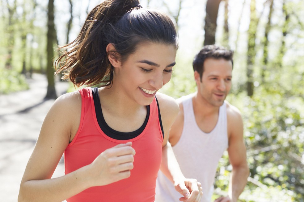 Homem e mulher correm e abrem o sorriso: exercício ajuda a amenizar o estresse do dia a dia (Foto: Getty Images)