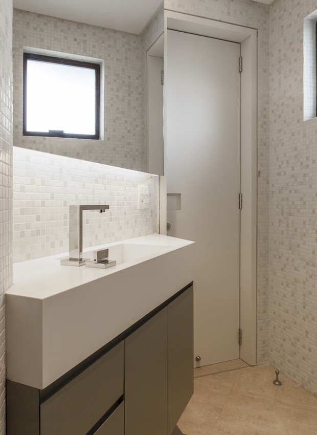 A planta triangular do banheiro desafiou os arquitetos. A cuba integrada à bancada ajudou a multiplicar o espaço e a criar um resultado elegante (Foto: Maíra Acayaba/Divulgação)