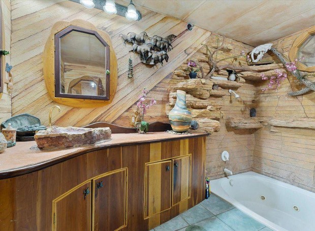 O banheiro da suíte principal faz par com as pinturas rupestres e parece uma pequena caverna de pedras (Foto: Zillow Gone Wild / Reprodução)