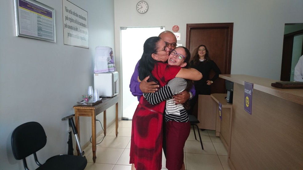 Família se abraça após receber a nova certidão (Foto: Júlia Martins/G1)