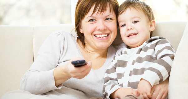 Mãe e filho assistindo televisão juntos no sofá (Foto: Shutterstock)