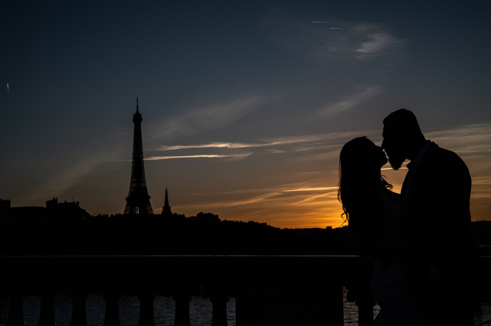 Casal se beija ao pôr do sol perto da Torre Eiffel, em Paris — Foto: MARTIN BUREAU/AFP
