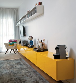 Com 4,50 m de comprimento, o móvel amarelo de laca dá a sensação de amplitude à sala estreita. “Ele dá apoio às salas de jantar e de estar, e mede apenas 35 cm de profundidade”, explica a arquiteta Nara Grossi, da Gema Arquitetura