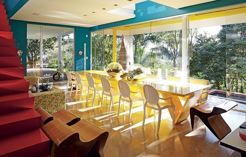 A sala de jantar em Goiânia ganhou muito mais bossa com árvores ao fundo e plantas. O amarelo da mesa com o verde da natureza se completam. Projeto do arquiteto Leo Romano