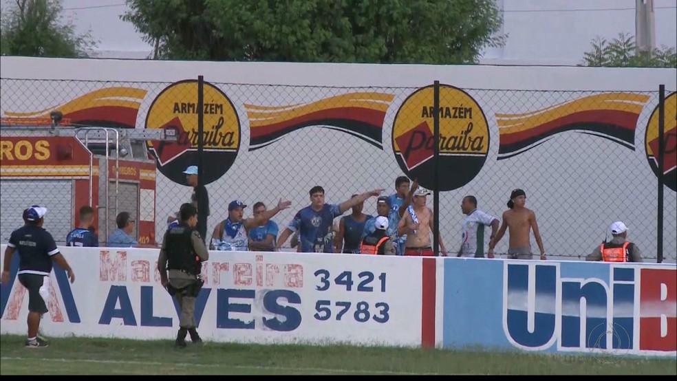 Separados do campo por um alambrado, torcedores do Atl�tico-PB s�o contidos por homens da PM (Foto: Reprodu��o / TV Para�ba)