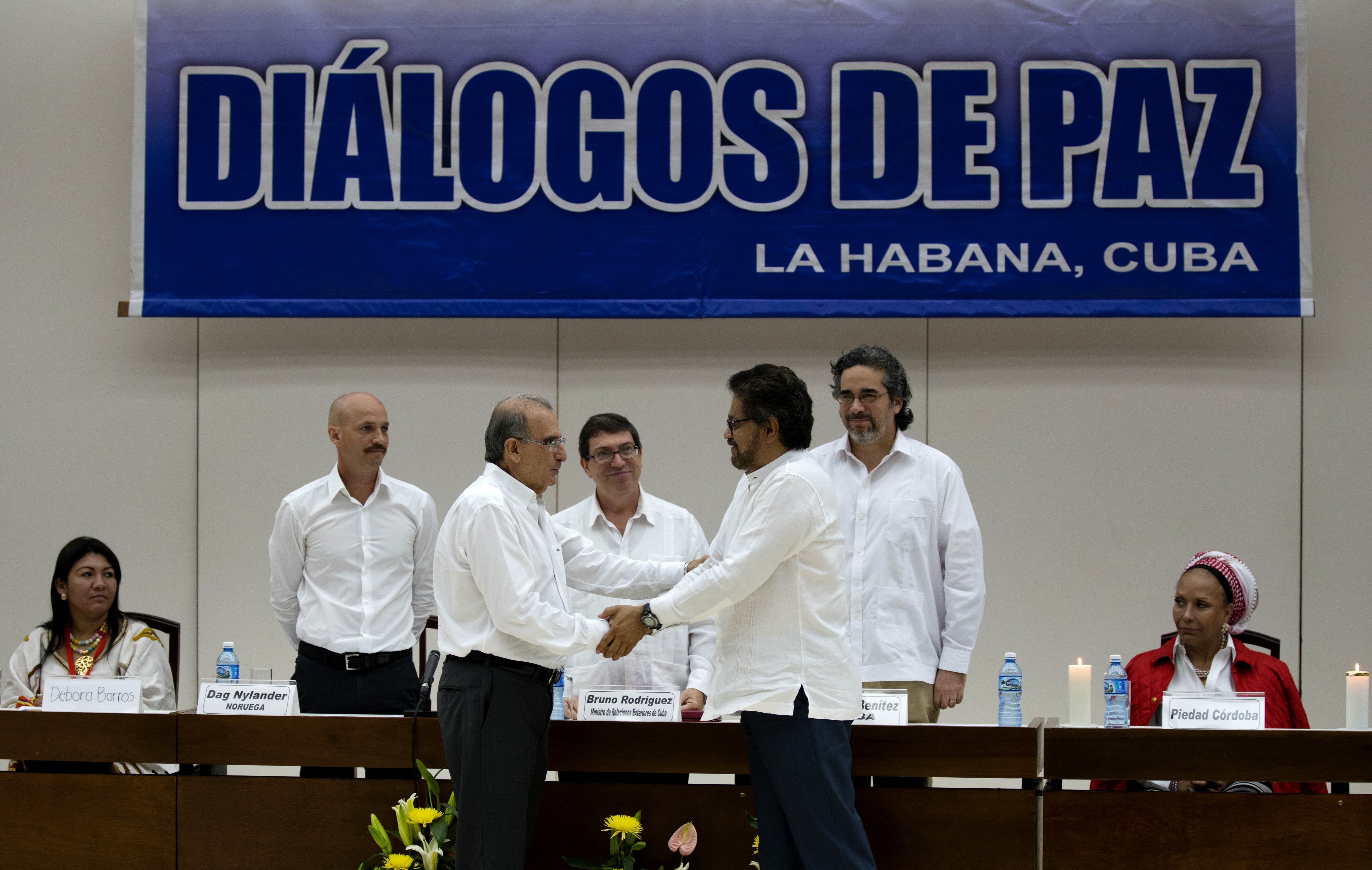 O chefe da equipe de negociação do governo colombiano Humberto de la Calle, na frente à esquerda, cumprimenta Ivan Marquez, negociador-chefe das Farc nesta terça-feira (15) em Havana (Foto: AP Photo/Ramon Espinos)