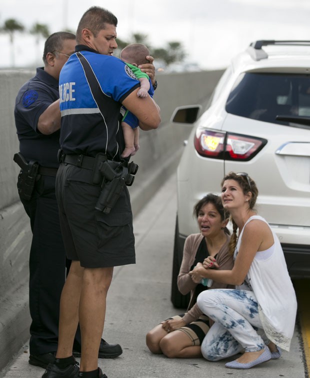 O policial Amauris Bastidas ajuda a socorrer o bebê de cinco meses Sebastian de la Cruz, que parou de respirar enquanto era levado de carro por sua tia em uma estrada na Califórnia (Foto: The Miami Herald, Al Diaz/AP)