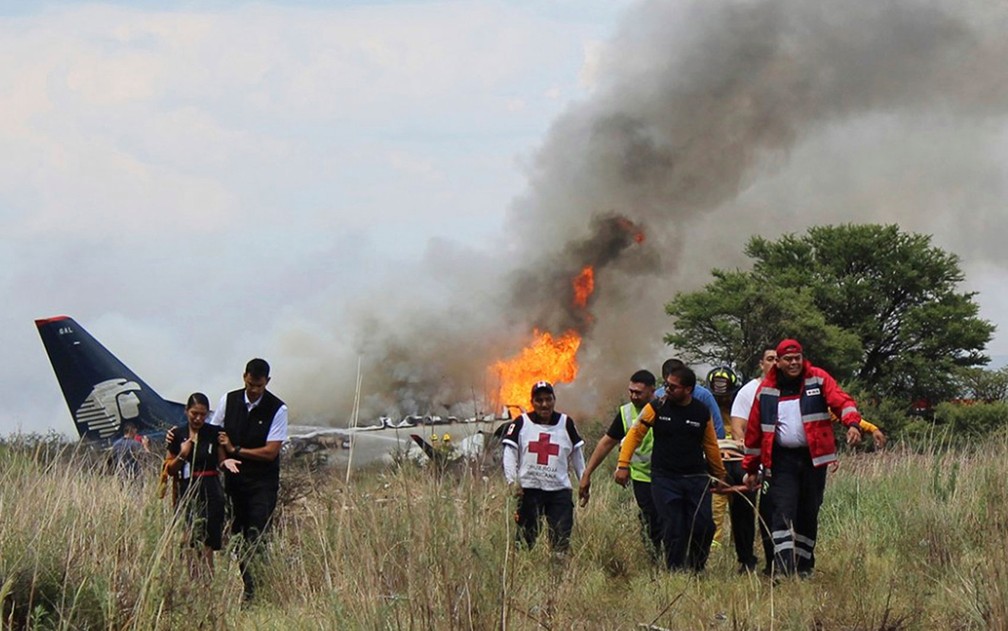 Socorristas carregam ferido em maca durante resgate apÃ³s acidente com aviÃ£o da AeromÃ©xico perto do aeroporto de Durango, no MÃ©xico, na terÃ§a-feira (31) (Foto: Red Cross Durango via AP)