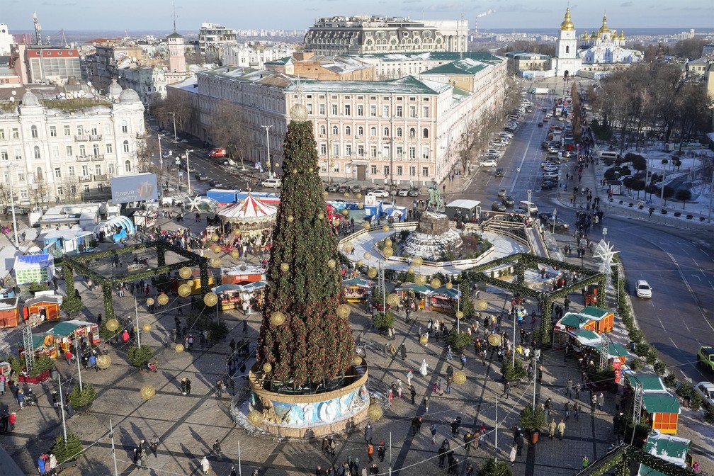 Pessoas caminham ao redor de uma árvore de Natal no centro de Kiev, Ucrânia, neste sábado (25) — Foto: Efrem Lukatsky/AP