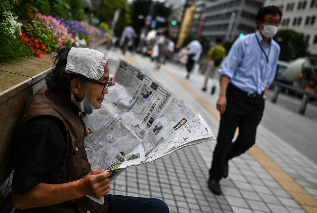 Homem lê jornal em uma rua de Tóquio, no Japão, na terça-feira (14)  — Foto: Charly Triballeau / AFP