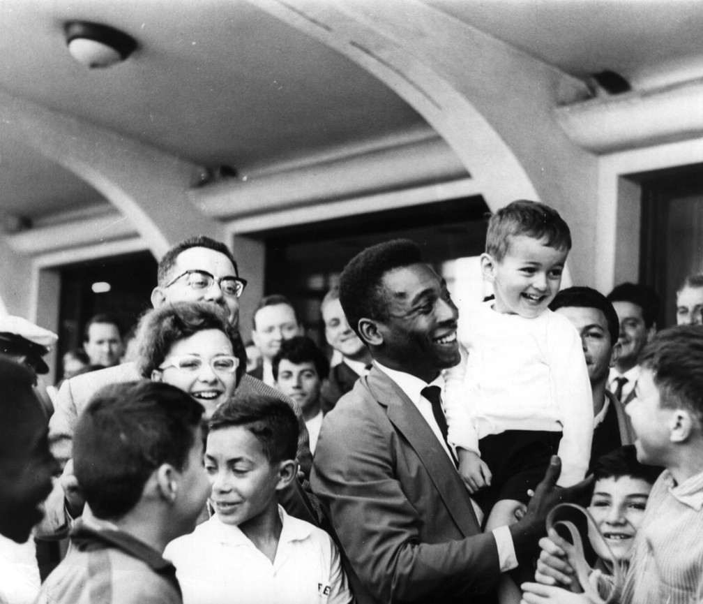 Pelé segura uma criança no colo ao ser recepcionado por torcedores no Aeroporto de Congonhas, em São Paulo, em julho de 1965 — Foto: Estadão Conteúdo/Arquivo
