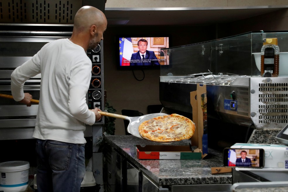 Funcionário de pizzaria em Nice, na França, assiste a discurso de Emmanuel Macron nesta segunda-feira (13) — Foto: Eric Gaillard/Reuters