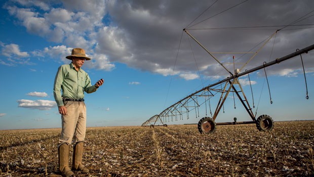 Amilton Costa, da SLC, usa o GPS para identificar áreas com maior produtividade da fazenda, em Goiás. À direita, uma máquina de irrigação move-se sozinha pelo campo, comandada por um algoritmo (Foto: Paralaxis)