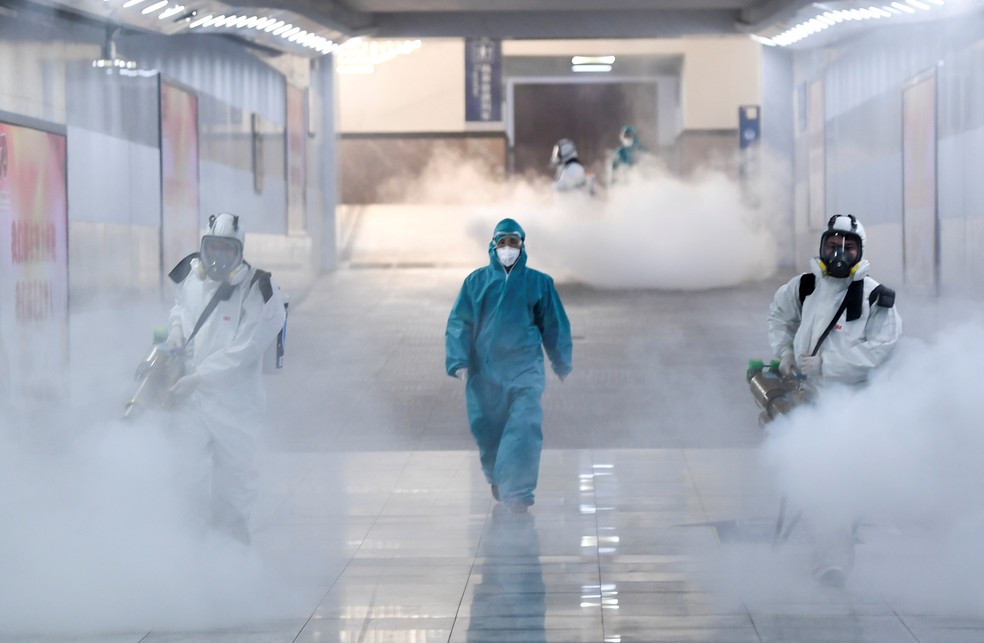 Voluntários com equipamento de proteção desinfetam uma estação ferroviária chinesa para combater o surto de novo coronavírus, em 4 de fevereiro de 2020 — Foto: cnsphoto/Reuters