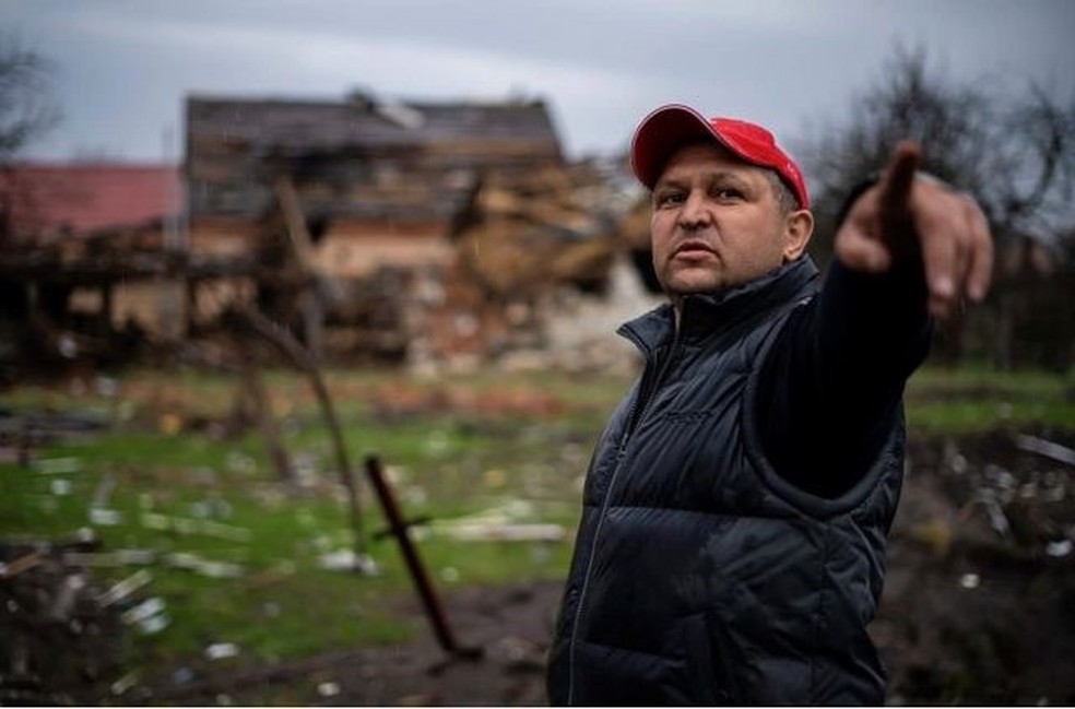 Um civil ucraniano aponta para o local em Kiev onde russos destruíram sua casa — Foto: BBC / CLAIRE JUDE PRESS